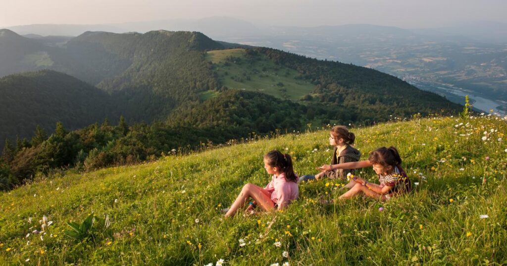 Des juniors assis sur l'herbe et admirent le paysage sur le grand colombier