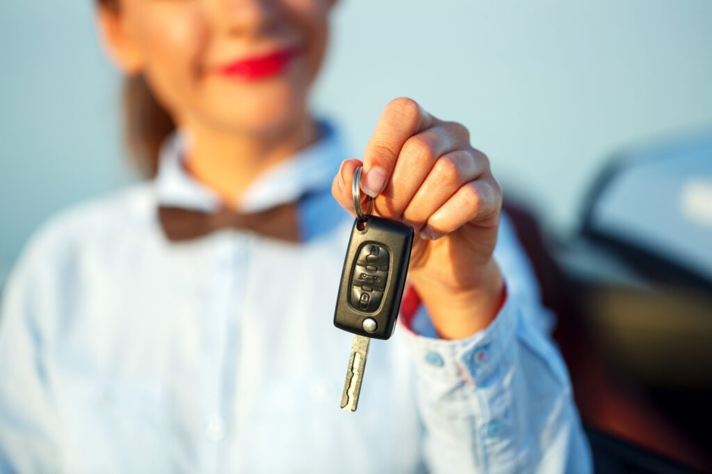 Jeune femme debout près d'un cabriolet avec des clés en main. Concept de location voiture